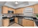 Modern kitchen featuring granite countertops, stainless steel appliances, and custom maple cabinetry at 20 Sylvia Pl, Oldsmar, FL 34677