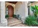 Charming front entrance with a wooden door, brick steps, and manicured plants at 1097 Eden Isle Ne Dr, St Petersburg, FL 33704