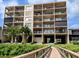 Condo building with multiple balconies, lush greenery, and bridge entrance at 19725 Gulf Blvd # 405, Indian Shores, FL 33785