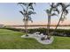 Outdoor patio seating area with table and benches overlooking water view with palm trees at sunset at 19725 Gulf Blvd # 405, Indian Shores, FL 33785
