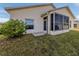 Back exterior view of the home featuring a glass enclosed sunroom, lawn, and partial landscaping at 24156 Buckingham Way, Punta Gorda, FL 33980