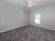 Cozy bedroom featuring a ceiling fan, a window with a view, and neutral colored carpet at 24156 Buckingham Way, Punta Gorda, FL 33980