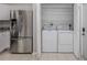 A laundry room with a side-by-side washer and dryer inside a closet and stainless steel refrigerator nearby at 24156 Buckingham Way, Punta Gorda, FL 33980