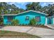 Charming, bright blue one-story home with beautiful landscaping, decorative window boxes, and a concrete driveway at 717 Carolina Ave, Tarpon Springs, FL 34689