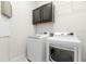 Close up of a white washer and dryer inside of a white laundry room with gray cabinets at 7602 S Desoto St, Tampa, FL 33616