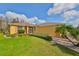 Single Gathering home showcasing lush lawn, colorful palm tree, shrubbery, and light colored exterior with dark shutters at 1123 Emerald Dunes Dr, Sun City Center, FL 33573