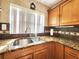 Close-up view of kitchen sink and granite countertops with custom wood cabinets at 35204 Ponderosa Rd, Zephyrhills, FL 33541