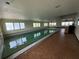 Large indoor swimming pool with many windows, a dark lane divider, and vintage-style tiles at 6170 7Th N Ave, St Petersburg, FL 33710