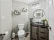 Cozy bathroom with modern vanity, round mirror, and decorative shelves above the toilet at 6324 Magnolia Trails Ln, Gibsonton, FL 33534