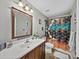 Bathroom with a wood vanity, decorative mirror, patterned shower curtain, and tile flooring at 6324 Magnolia Trails Ln, Gibsonton, FL 33534