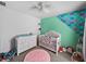 A cozy Bedroom featuring a white crib, dresser, themed wall art and carpet flooring at 6324 Magnolia Trails Ln, Gibsonton, FL 33534