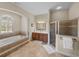 An en-suite bathroom featuring soaking tub, glass shower and vanity with elegant lighting at 1111 Carriage Park Dr, Valrico, FL 33594