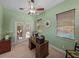 A dedicated office space features a ceiling fan, a wooden desk, and natural light from the doors to the lanai at 1111 Carriage Park Dr, Valrico, FL 33594