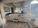 Bathroom with double vanity, a large mirror, and a view of the bathtub next to a window at 1530 Davenport Dr, New Port Richey, FL 34655