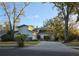 Charming home with a red front door, mature trees, long driveway and a well-manicured front lawn at 1735 Tall Pine Cir, Safety Harbor, FL 34695