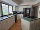 Well-lit kitchen boasts white cabinets, stainless steel refrigerator, and a large window with backyard views at 1735 Tall Pine Cir, Safety Harbor, FL 34695