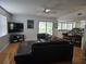 Open-concept living room features hardwood floors, a ceiling fan, and a comfortable black leather sofa at 1735 Tall Pine Cir, Safety Harbor, FL 34695