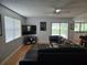 Bright living room with hardwood floors, a ceiling fan, television, and access to outdoor light and views at 1735 Tall Pine Cir, Safety Harbor, FL 34695