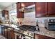 Close up of kitchen with stainless gas range, granite counters, and dark cabinets at 4748 Ballast Crest Cv, Land O Lakes, FL 34638