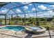A screened in pool with a spa sits on a brick patio surrounded by grass and shrubbery at 4748 Ballast Crest Cv, Land O Lakes, FL 34638