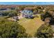 Aerial view of estate home with expansive lawn, tiki bar, pool, and waterfront views at 6785 Burning Tree Dr, Seminole, FL 33777