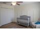 A cozy Bedroom with a gray crib, a chair, and a closet at 18311 Arbor Crest Dr, Hudson, FL 34667