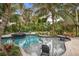 An outdoor pool area features a tiki hut, spa, lush landscaping, and comfortable seating at 319 26Th W St, Bradenton, FL 34205