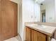 Bathroom with vanity, sink, wood cabinets, large mirror, and tiled flooring next to a bedroom door at 9888 Lake Seminole E Dr, Largo, FL 33773