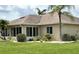 View of the rear exterior showcasing an enclosed porch, well maintained lawn, and lush landscaping at 1311 Caloosa Lake Ct, Sun City Center, FL 33573