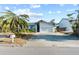 Exterior front view of a one-story home with a large driveway, attached garage, and lush landscaping at 155 1St W St, Tierra Verde, FL 33715