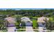 Aerial view of a single-story home with lush landscaping, a brick driveway, and a two-car garage at 15856 Cobble Mill Dr, Wimauma, FL 33598