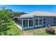 Rear exterior view of home with screened-in lanai and lush landscaping at 15856 Cobble Mill Dr, Wimauma, FL 33598