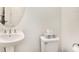 Cozy powder room featuring a pedestal sink, round mirror, and a toilet with striped tissue box at 8463 Canyon Creek Trl, Parrish, FL 34219