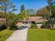 Charming single-story home with a well-maintained lawn and a long driveway, framed by lush greenery and a blue sky at 1214 Royal Oak Dr, Dunedin, FL 34698