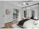 This staged bedroom features wood floors, mirrored closet, and sliding doors leading to a balcony at 2730 5Th Ct, Palm Harbor, FL 34684