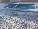 In-ground pool with a bright blue interior surrounded by sand at 6923 Dartmouth N Ave, St Petersburg, FL 33710
