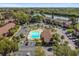 Wide aerial view showcasing the community pool, clubhouse, ample parking, and lush landscaping near a scenic lake at 880 S Village Lake N Dr # 106, St Petersburg, FL 33716