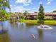 View of a fountain and the condo building overlooking the pond with mature trees in the Clearwater, Florida community at 880 S Village Lake N Dr # 106, St Petersburg, FL 33716