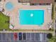 Aerial view of a rectangular community pool with bright blue water, surrounded by lounge chairs and a parking lot at 880 S Village Lake N Dr # 106, St Petersburg, FL 33716