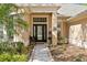 Elegant front entrance with a decorative glass door and lush landscaping, perfect for a welcoming first impression at 10240 Shadow Branch Dr, Tampa, FL 33647