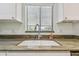 Close up of the kitchen sink featuring bright white cabinets and a modern faucet at 215 Valencia Blvd # 106, Belleair Bluffs, FL 33770