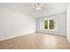 Bright bedroom with neutral tile flooring, ceiling fan, and large window offering backyard views at 4251 Whittner Dr, Land O Lakes, FL 34639
