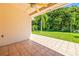 Covered patio with patterned tile and ceiling fan, opening up to a green lawn with mature trees at 4251 Whittner Dr, Land O Lakes, FL 34639
