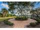 Landscaped outdoor space with brick walkway, seating, manicured shrubs, and shade tree at 2775 Kipps Colony S Dr # 105, Gulfport, FL 33707