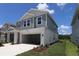 Two-story home featuring a two-car garage and blue siding against a clear, sunny sky at 28965 Orange Berry Dr, Wesley Chapel, FL 33543