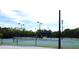 Outdoor tennis court with lights, dark fencing, a covered area with a bench, and plenty of space to play at 404 Manns Harbor Dr, Apollo Beach, FL 33572