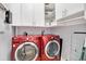 Well-organized laundry room with red front-loading machines, white cabinets, and open shelving at 777 N Ashley Dr # 1614, Tampa, FL 33602