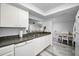 Modern kitchen with granite countertops, white cabinets, stainless steel sink, and an adjacent dining area at 9204 Golf View Dr, New Port Richey, FL 34655
