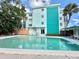 Exterior shot of a condo complex featuring a community pool, a cabana, and tropical landscaping at 100 Waverly Way # 302, Clearwater, FL 33756
