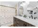 Bright bathroom featuring a wood vanity with dual sinks, round mirrors, and a tiled walk-in shower at 12526 Spottswood Dr, Riverview, FL 33579